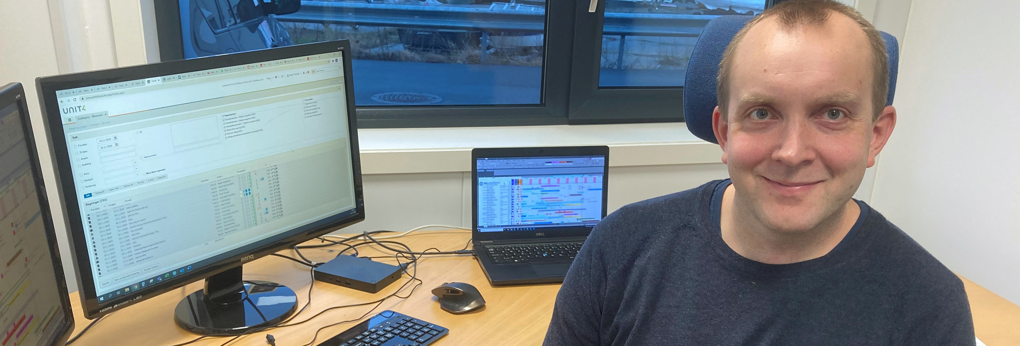 Smilende mann sitter ved PC