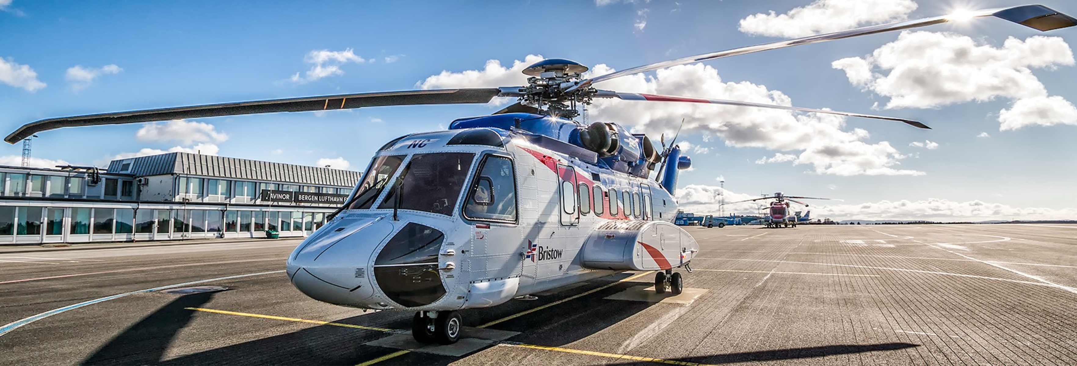Helicopter on ground with blue sky and clouds in the back