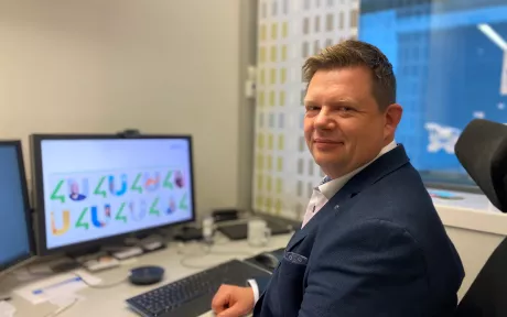 Smilende mann sitter ved PC