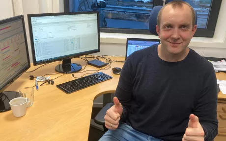 Smilende mann sitter ved PC