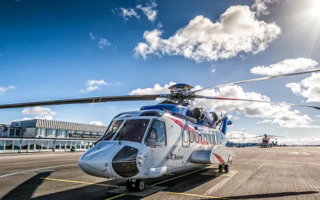 Helicopter on ground with blue sky and clouds in the back